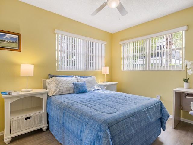 bedroom with ceiling fan, wood-type flooring, and a textured ceiling