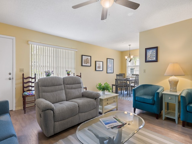 living room with a textured ceiling, ceiling fan with notable chandelier, and hardwood / wood-style flooring