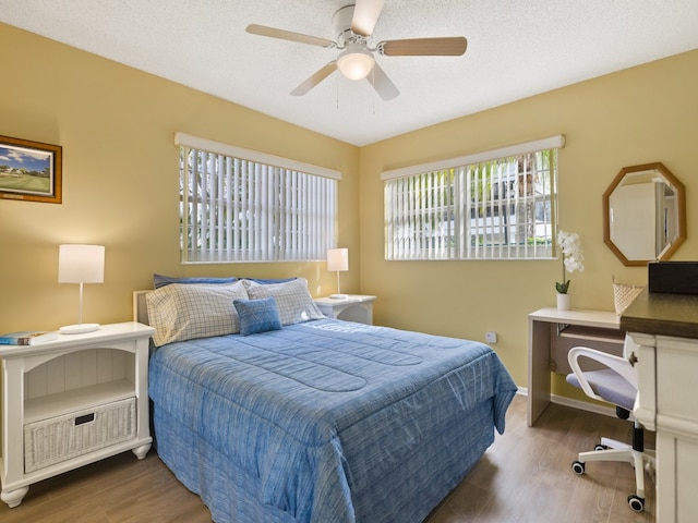 bedroom with hardwood / wood-style floors, ceiling fan, and a textured ceiling