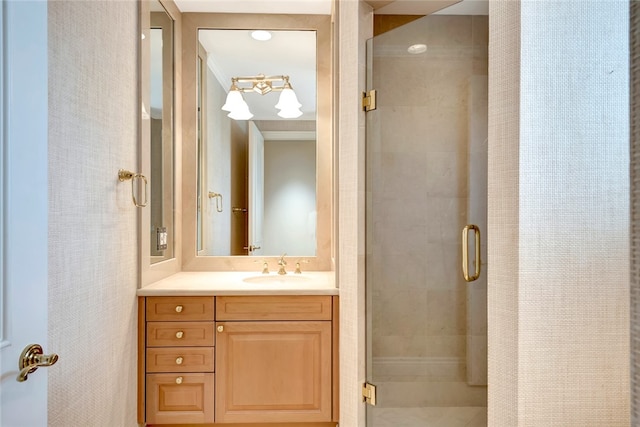 bathroom with a shower with shower door, vanity, and ornamental molding