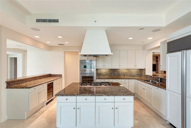 kitchen featuring white cabinetry, custom range hood, appliances with stainless steel finishes, and dark stone counters