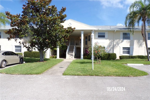 view of front of property with a front lawn, stucco siding, stairs, and covered porch
