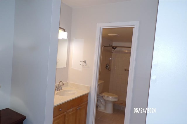 bathroom with toilet, tiled shower, vanity, and tile patterned floors