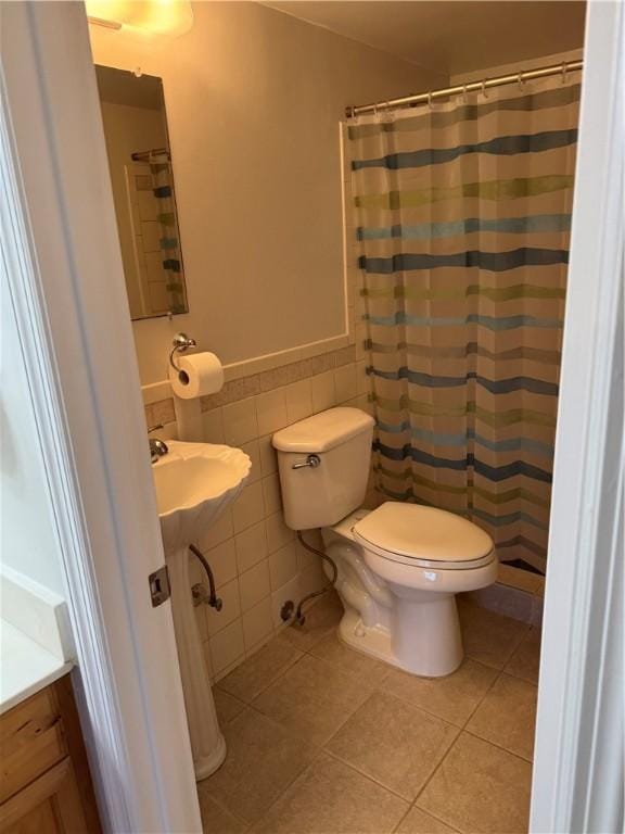 full bath with toilet, tile patterned floors, tile walls, and a shower with shower curtain