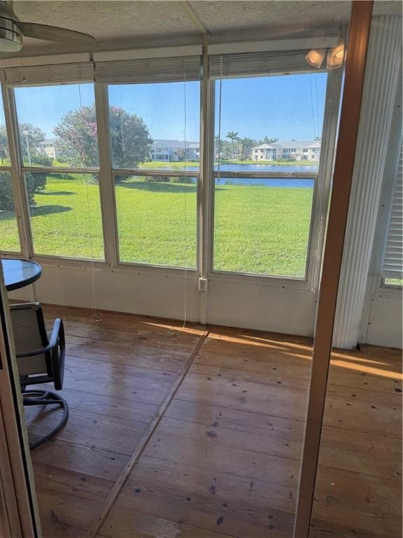 unfurnished sunroom featuring a water view, plenty of natural light, and a ceiling fan