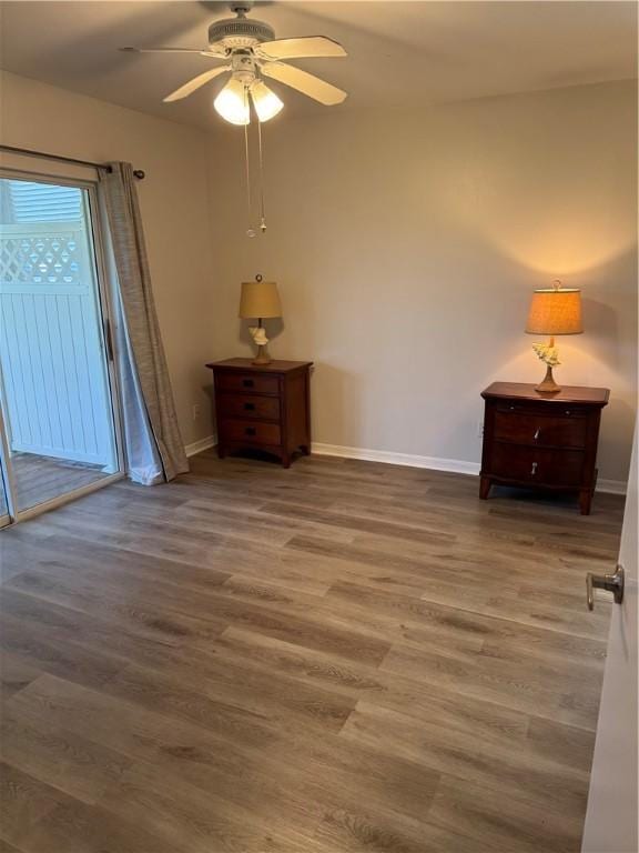 unfurnished bedroom with baseboards, wood finished floors, access to outside, and a ceiling fan