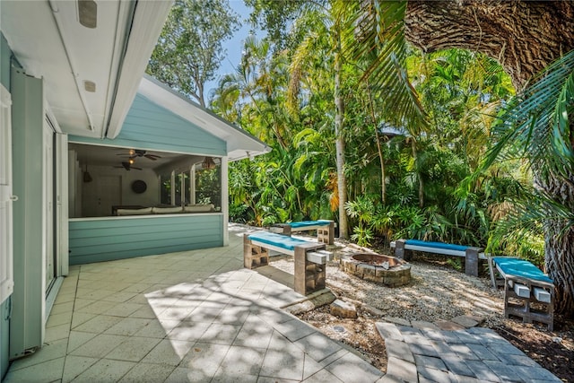 view of patio featuring a sunroom, ceiling fan, and an outdoor fire pit