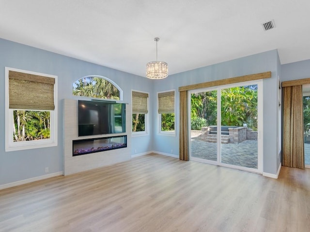 unfurnished living room with a notable chandelier and light wood-type flooring