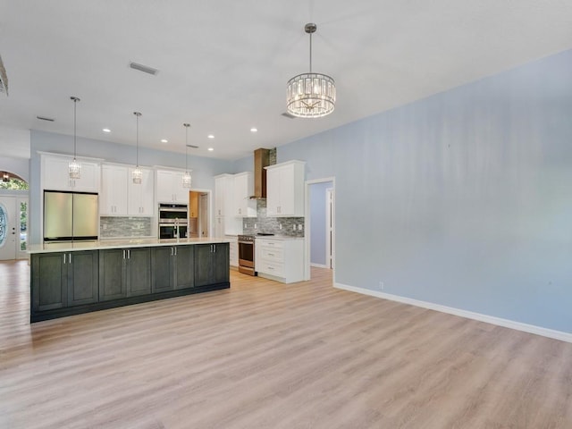 kitchen with pendant lighting, a large island with sink, white cabinets, and appliances with stainless steel finishes