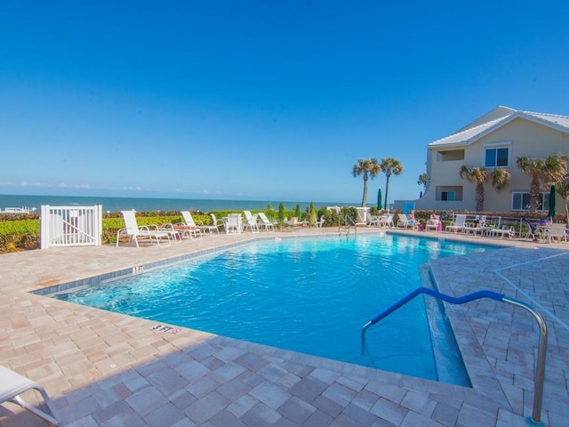 view of swimming pool featuring a patio and a water view