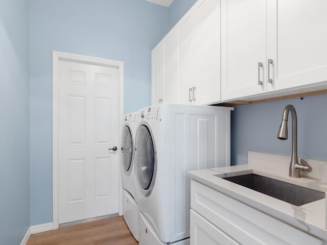 washroom with cabinets, separate washer and dryer, sink, and light wood-type flooring