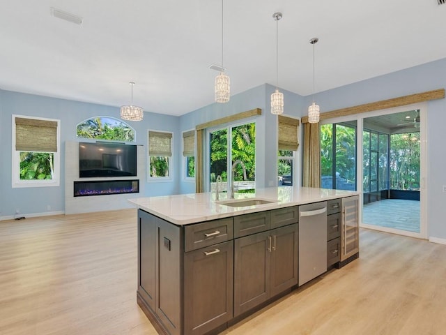 kitchen featuring dishwasher, sink, light stone counters, and decorative light fixtures