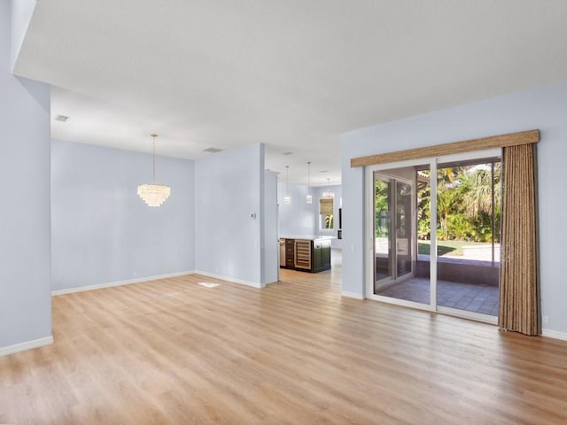 unfurnished living room featuring a chandelier and light hardwood / wood-style floors