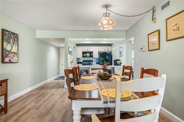 28 Plantation Dr Unit 204, Vero Beach, FL 32966 - dining area with light wood-style floors, a textured ceiling, and baseboards