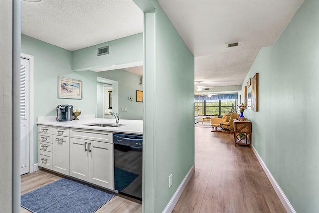 28 Plantation Dr Unit 204, Vero Beach, FL 32966 - bar area with black dishwasher, a sink, light wood-type flooring, a textured ceiling, and baseboards