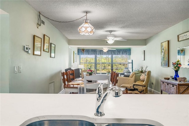 28 Plantation Dr Unit 204, Vero Beach, FL 32966 - kitchen with a sink, a textured ceiling, a ceiling fan, baseboards, and light countertops