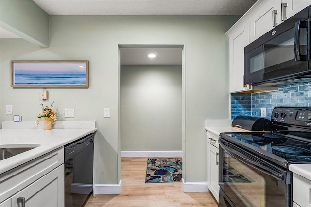 28 Plantation Dr Unit 204, Vero Beach, FL 32966 - kitchen with black appliances, light wood finished floors, decorative backsplash, white cabinetry, and light countertops