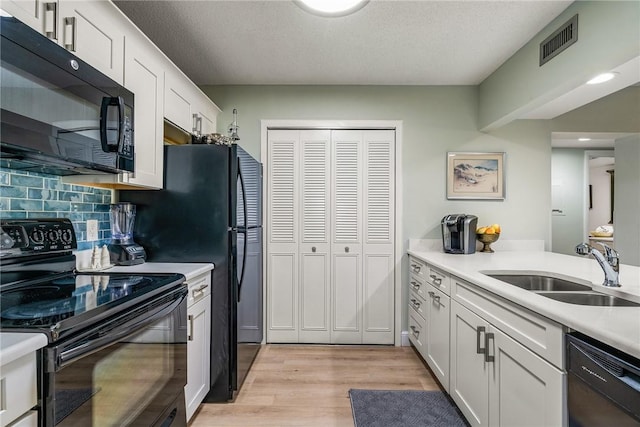28 Plantation Dr Unit 204, Vero Beach, FL 32966 - kitchen with black appliances, a sink, white cabinets, light wood-type flooring, and light countertops
