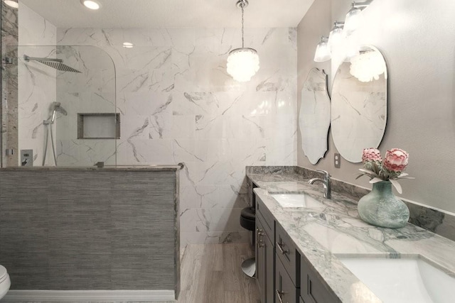 bathroom featuring toilet, vanity, and tiled shower