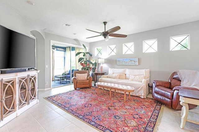 living room featuring ceiling fan, light tile patterned floors, and a textured ceiling