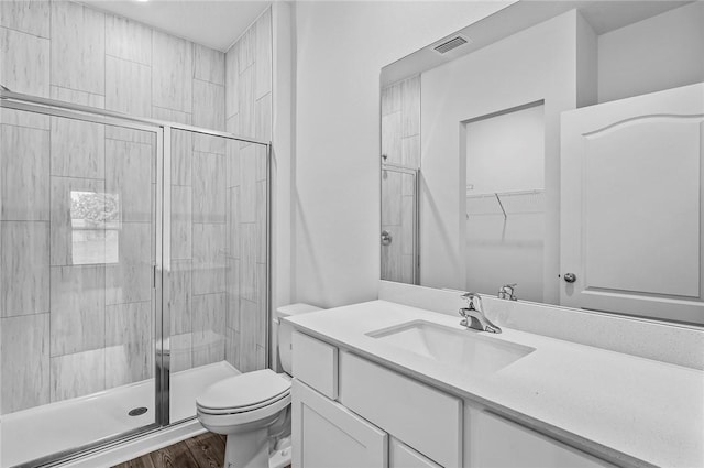 8715 98th Ct, Vero Beach, FL 32967 - bathroom featuring a stall shower, vanity, toilet, wood finished floors, and a walk in closet