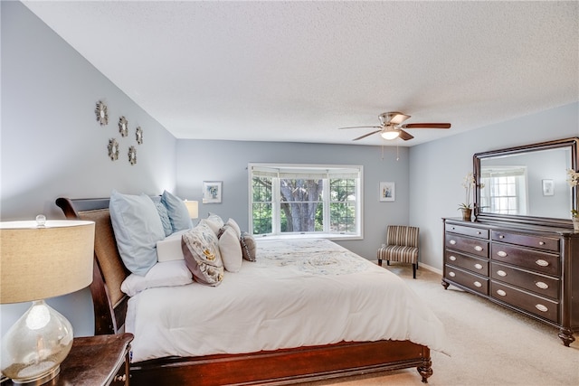 bedroom featuring a textured ceiling, light colored carpet, and ceiling fan