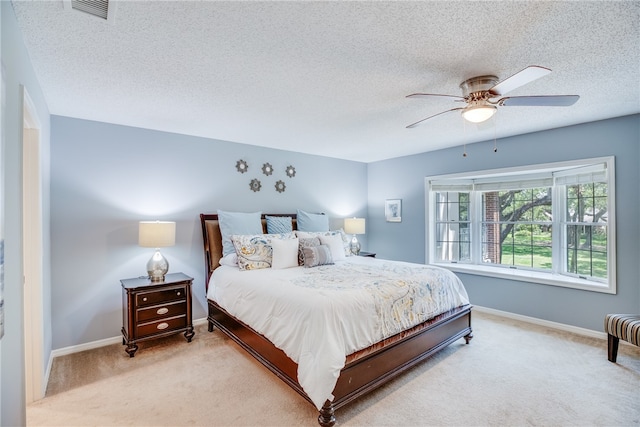 bedroom featuring ceiling fan, light colored carpet, and a textured ceiling