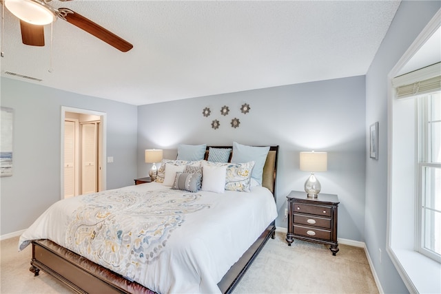 bedroom with light colored carpet, multiple windows, and ceiling fan
