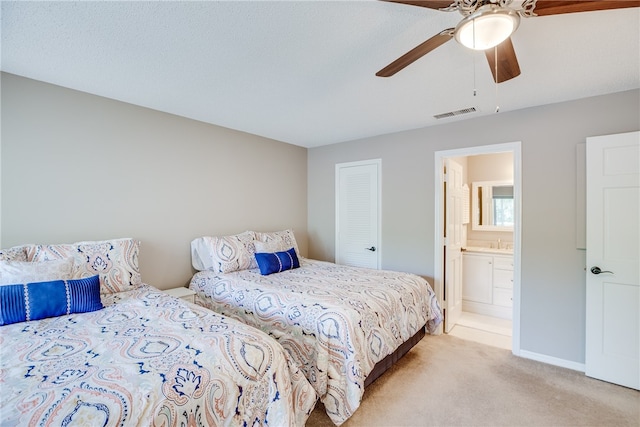 bedroom featuring ensuite bath, ceiling fan, sink, light colored carpet, and a closet