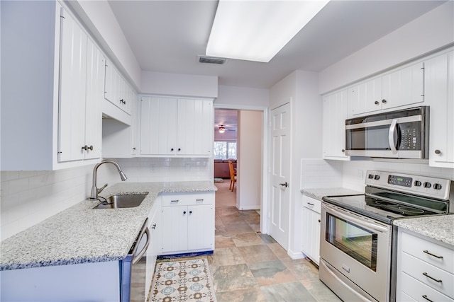 kitchen with white cabinets, sink, light stone countertops, and stainless steel appliances