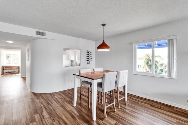 dining area with hardwood / wood-style floors and a textured ceiling