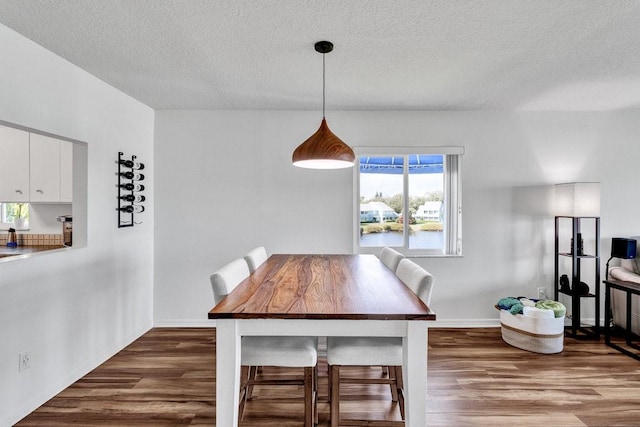 dining space featuring wood-type flooring and a textured ceiling