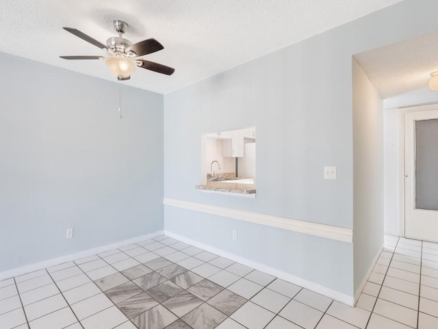 tiled empty room featuring ceiling fan, sink, and a textured ceiling