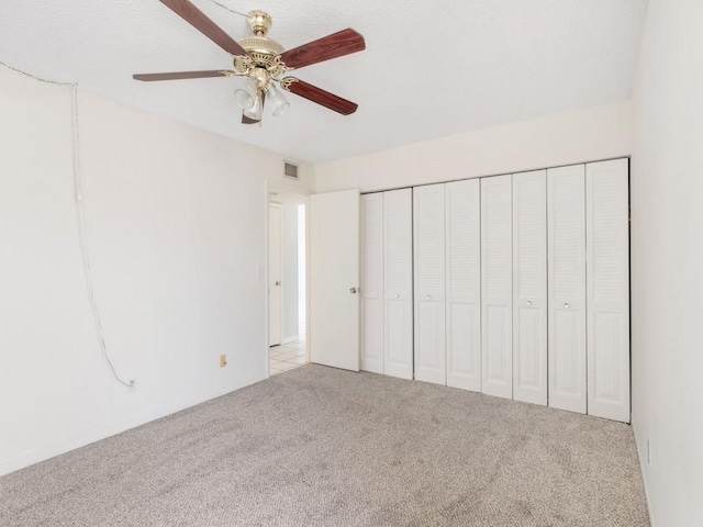 unfurnished bedroom with light carpet, ceiling fan, and a closet