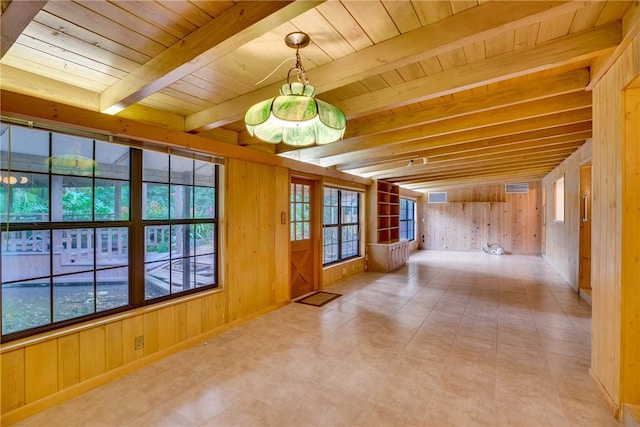 interior space featuring beam ceiling, wooden walls, plenty of natural light, and wood ceiling