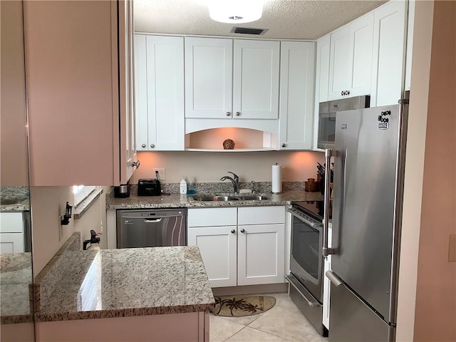 4 Vista Gardens Trl Unit 103, Vero Beach, FL 32962 - kitchen featuring stainless steel appliances, white cabinets, light stone countertops, and light tile patterned floors