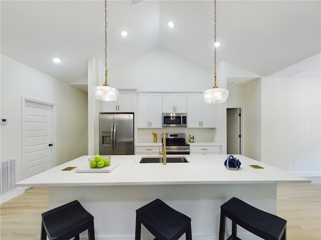 kitchen with a spacious island, light hardwood / wood-style flooring, pendant lighting, and appliances with stainless steel finishes