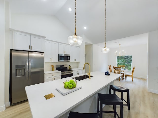 kitchen with white cabinets, a center island with sink, sink, decorative light fixtures, and stainless steel appliances