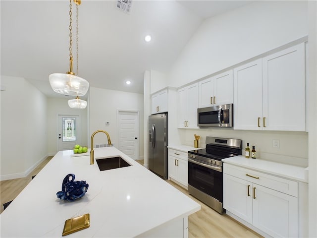 kitchen with white cabinetry, sink, pendant lighting, lofted ceiling, and appliances with stainless steel finishes