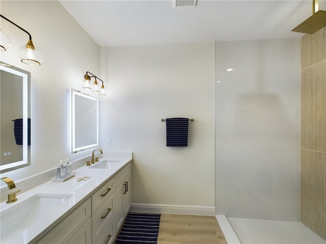 bathroom with hardwood / wood-style floors, vanity, and tiled shower