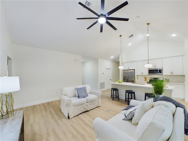 living room featuring high vaulted ceiling, light hardwood / wood-style flooring, ceiling fan, and sink