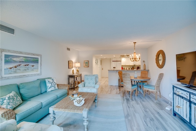 living room with light hardwood / wood-style floors and an inviting chandelier