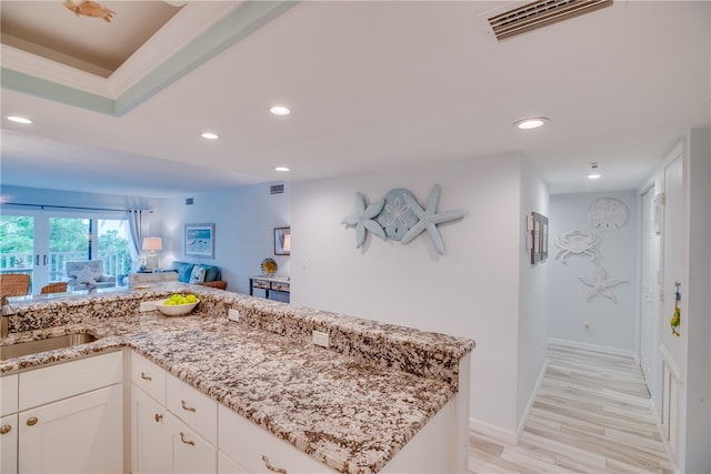 kitchen featuring light stone countertops, white cabinetry, sink, and light hardwood / wood-style flooring