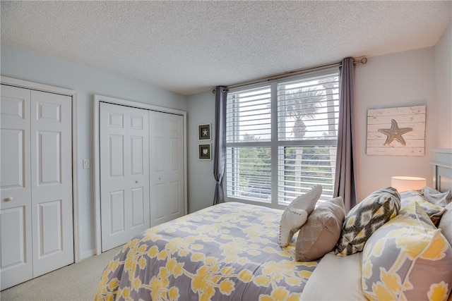 carpeted bedroom with a textured ceiling and two closets