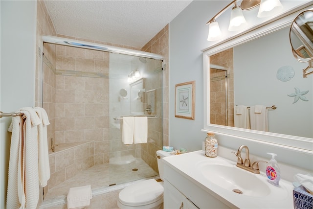 bathroom featuring toilet, vanity, a textured ceiling, and a shower with shower door