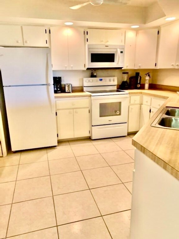 kitchen with white cabinets, sink, light tile patterned floors, and white appliances