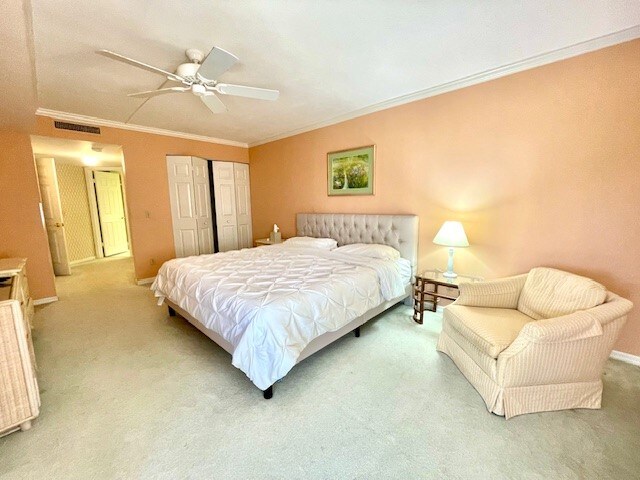 carpeted bedroom featuring ceiling fan and ornamental molding