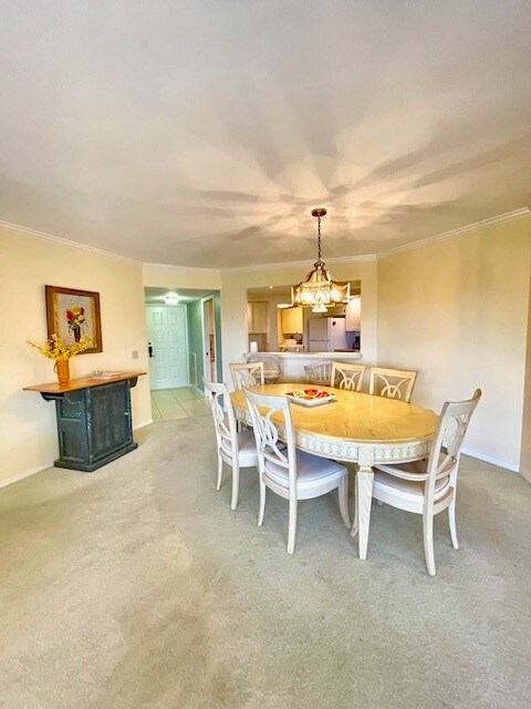 dining room featuring light carpet, crown molding, and a chandelier