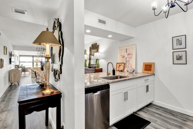 kitchen featuring sink, dishwasher, white cabinetry, light stone counters, and wood-type flooring