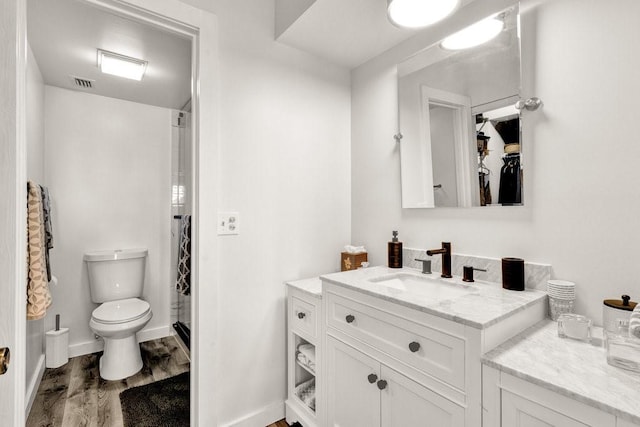 bathroom with vanity, hardwood / wood-style flooring, a shower, and toilet